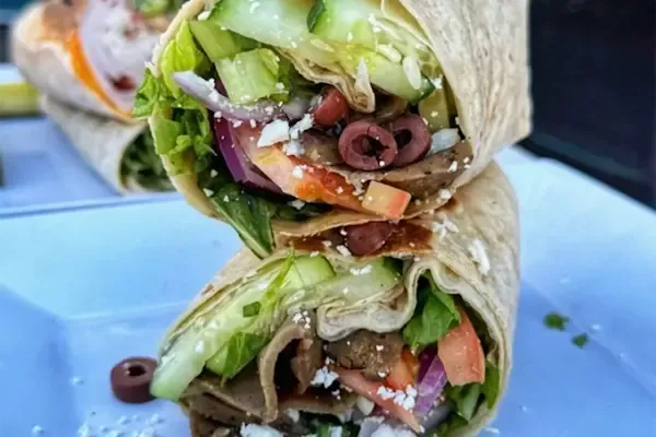 Savor the delicious flavors of our flame-broiled, hand-carved gyro nestled in a soft flour tortilla, with creamy house-made tzatziki sauce. Freshly sliced tomatoes, crisp thinly sliced red onions, refreshing organic cucumbers, feta cheese, briny Kalamata olives, and crunchy romaine lettuce, this wrap is a Mediterranean delight in every bite.