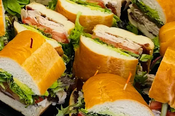 Each half sandwich is loaded with savory ham, bold salami, rich mortadella, and creamy provolone cheese, complemented by juicy sliced tomatoes, crisp red onions, peppery baby organic arugula, and zesty banana peppers. Finished with a spread of mayo, mustard, and a drizzle of our signature house-made Italian dressing, all nestled in a freshly baked hoagie roll.