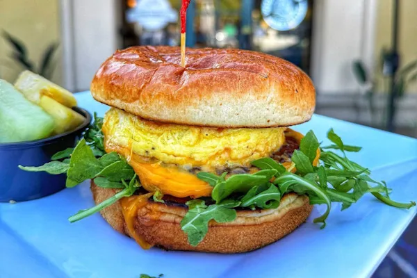 Featuring a sausage patty, fluffy scrambled eggs, melted American yellow cheddar cheese, fresh organic arugula topped with our special house-made garlic aioli on a buttery brioche bun.