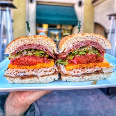 Sliced oven-roasted Turkey breast, Salami, thick cut bacon, Vermont cheddar cheese, shredded Romaine lettuce, house-pickled onions, tomatoes, spicy Italian seasoning, topped with House Italian dressing, house peppercorn sauce on a Dutch crunch roll