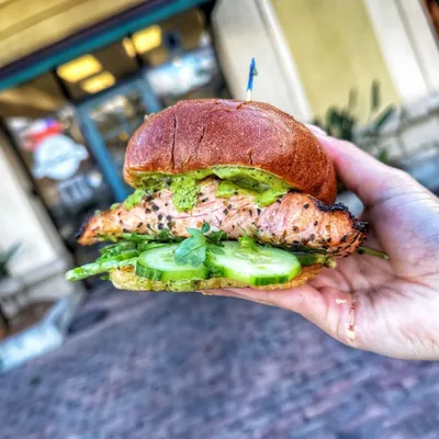 Grilled Wild-Caught Salmon, arugula, thinly sliced organic cucumbers, garlic Cilantro dressing on a Brioche Bun